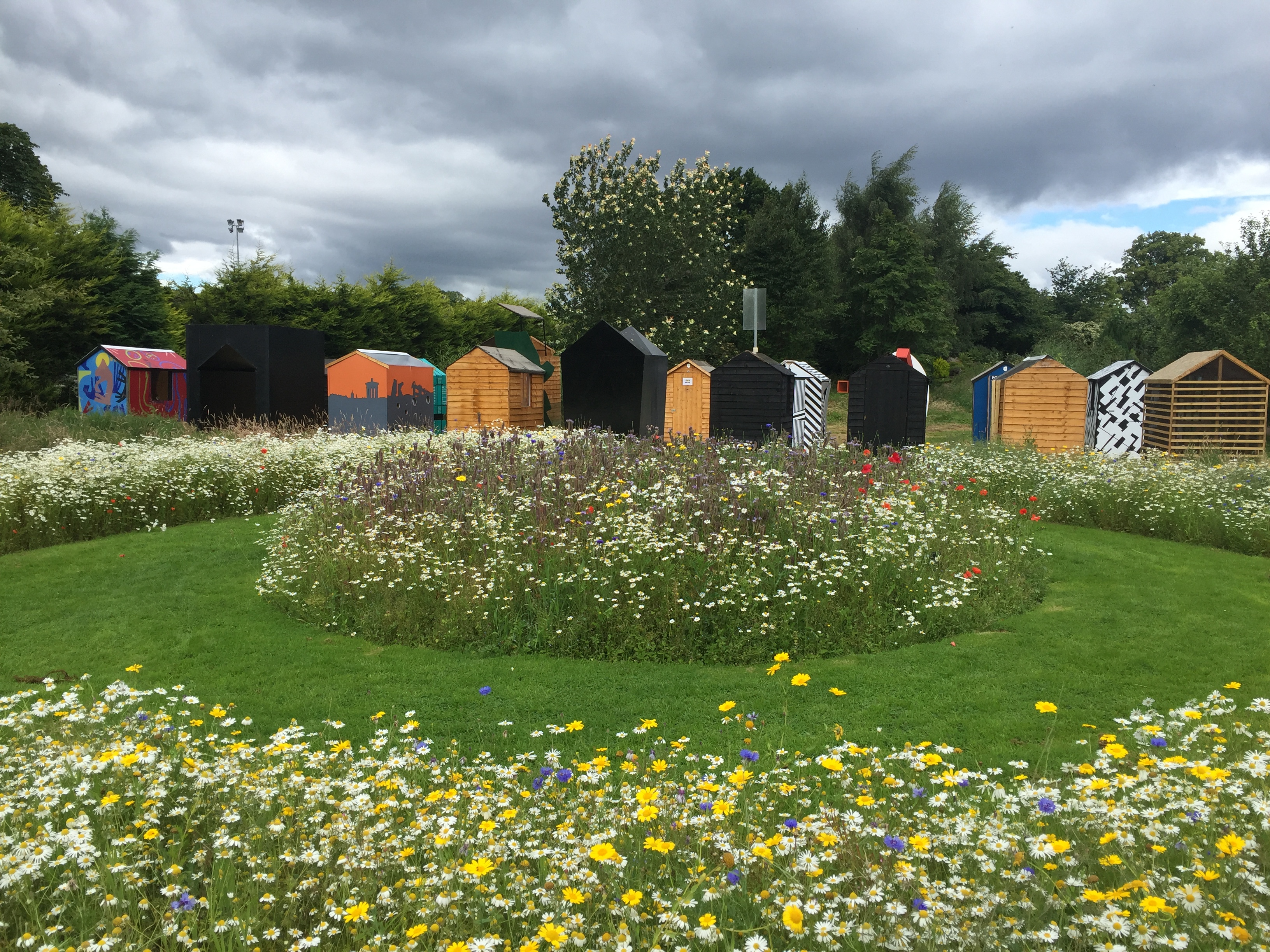 The Ideal Hut Show sheds in Inverness Botanics...with the far mot=re impressive wild flower meadow in the foreground.